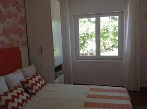 A bedroom with a bed, a window with curtains, and a wall with a floral pattern. - Charming home in the Algarve near the best golf courses (Olhos de Água)