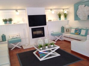 Ein Wohnzimmer mit Flachbildfernseher, Kamin, Sofa und Couchtisch mit Dekoration.