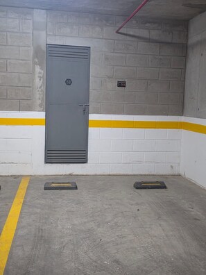 Een parkeergarage met een grijze deur waarop '68' staat en een bord met '2-304'.