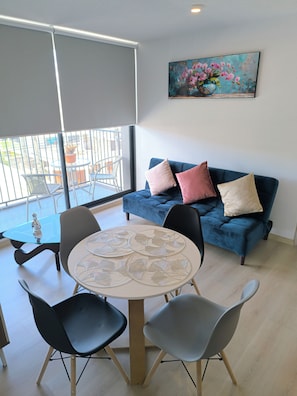 A modern living area with a round glass table, black and grey chairs, a blue sofa with cushions, and a painting of pink flowers on the wall. - Vista Hermosa neighborhood, Quito, near the U.S. Embassy and Solca Hospital (Quito)