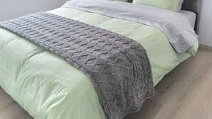 A bed with a grey headboard, green bedding, and a grey blanket. - Vista Hermosa neighborhood, Quito, near the U.S. Embassy and Solca Hospital (Quito)