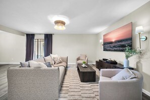 A modern living room with a sofa, armchairs, a coffee table, and a painting of a sunset over the ocean. - The perfect gem in the heart of Phoenix Biltmore! (Phoenix)