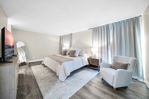 A modern bedroom with a large bed, a nightstand, a chair, and a TV. - The perfect gem in the heart of Phoenix Biltmore! (Phoenix)