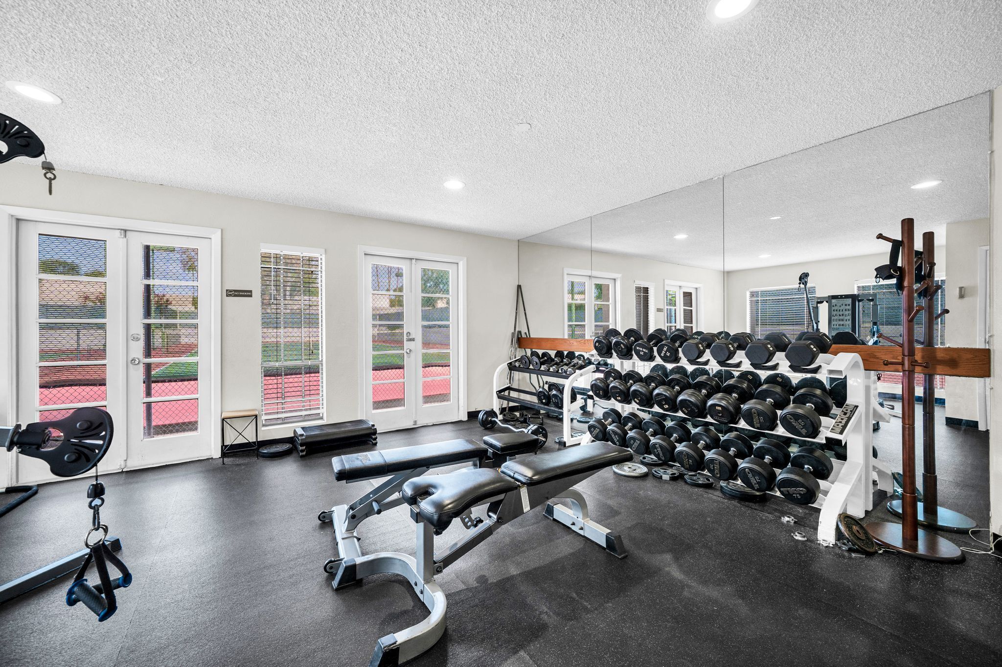 A gym with weightlifting equipment, benches, and a mirrored wall.