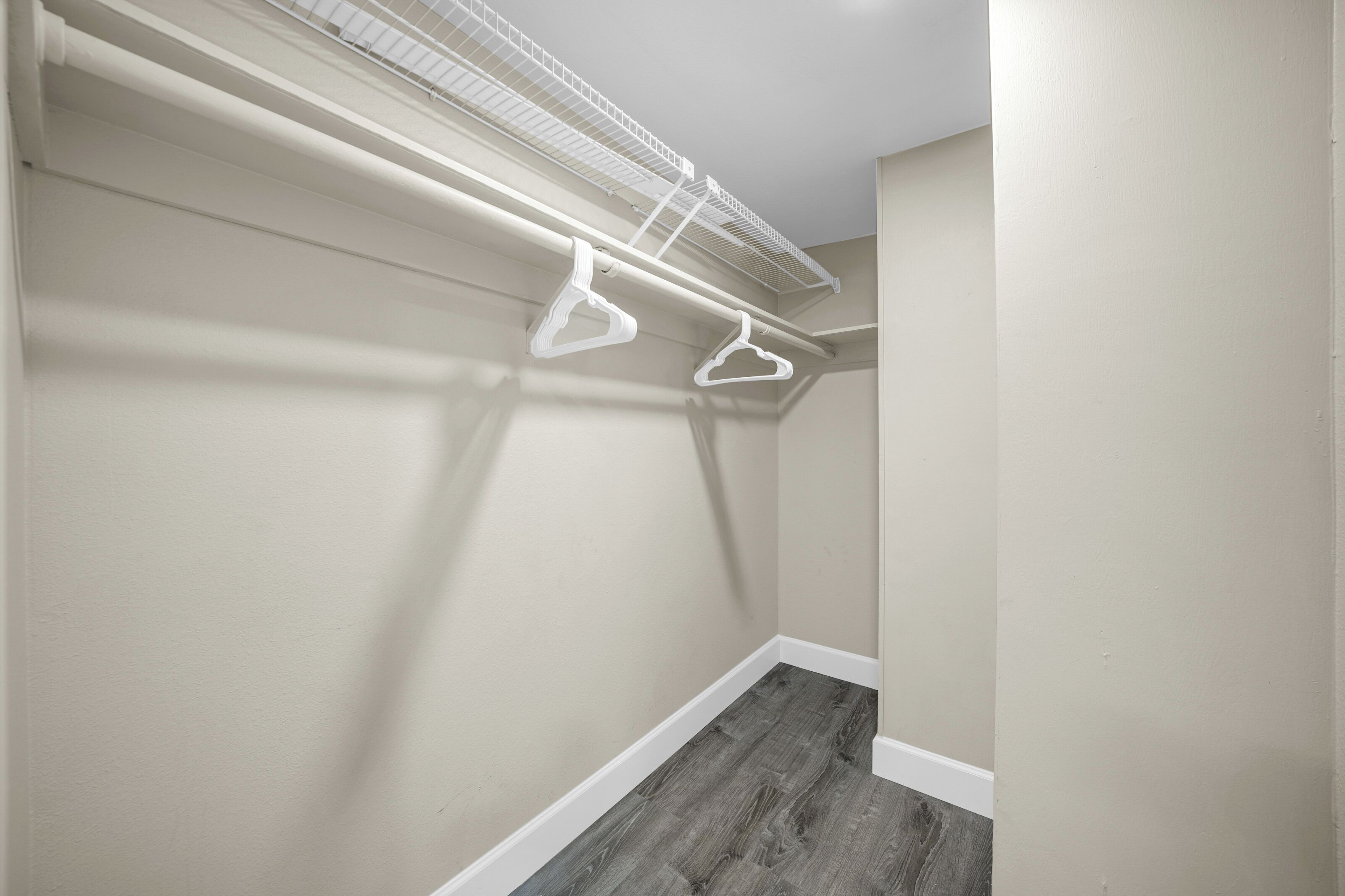 Armadio a muro con pavimento in legno, pareti bianche e un soffitto con bocchetta bianca.