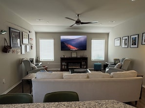 A living room with a large flat-screen TV, a ceiling fan, and a fireplace. - Ride to Bella Vista 3/4 Mi · Bike Garage · Fenced Yard, Dogs · Fireplace/grill (Pea Ridge)