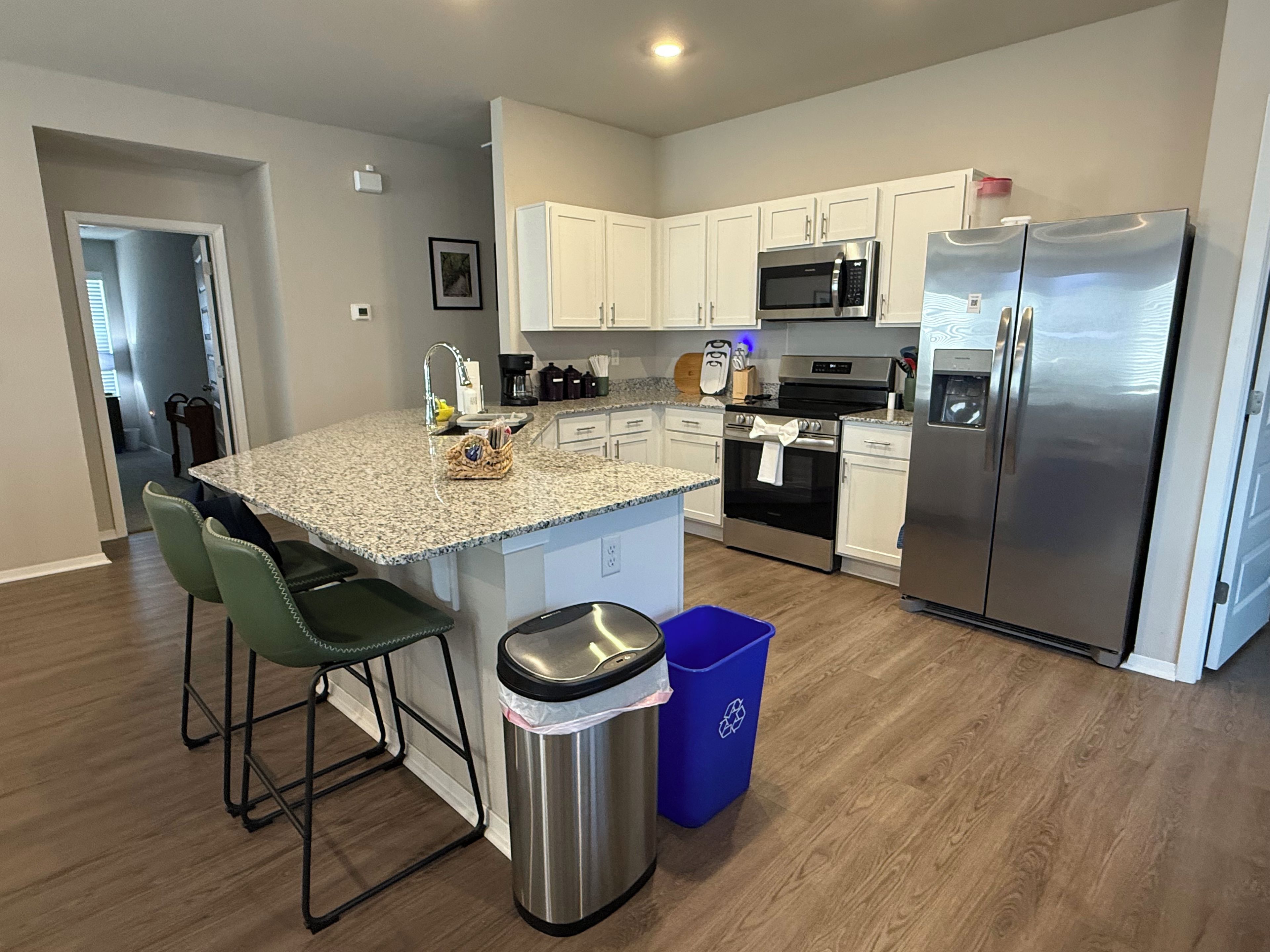 A modern kitchen with white cabinets, stainless steel appliances, and a granite countertop.