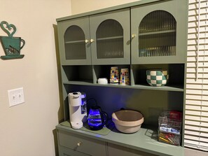 A kitchenette with a coffee maker, kettle, and a bowl on the counter. - Ride to Bella Vista 3/4 Mi · Bike Garage · Fenced Yard, Dogs · Fireplace/grill (Pea Ridge)