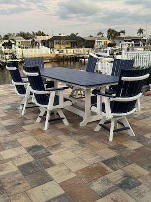 An outdoor seating area with a table and chairs, a dock with boats, and a waterfront view. - Beautiful beach house getaway (New Port Richey)