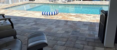 A pool area with lounge chairs and a floating pool toy.