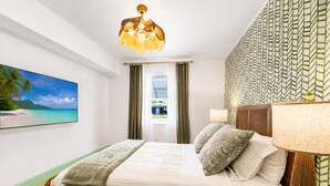 Une chambre d’hôtel avec un lit, une télévision, une fenêtre avec des rideaux, un mur à motifs et un luminaire au plafond.