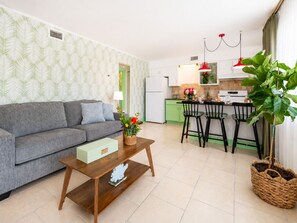 A living room with a sofa, a coffee table, and a kitchen area with a dining table and chairs. - Treasure Island Getaway | Walk to the beach | Pet-friendly (Treasure Island)