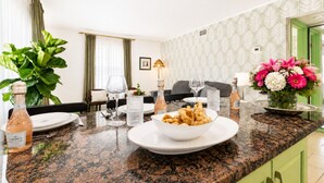 Un coin repas avec un plan de travail en marbre, un bol de nourriture, des verres à vin et une bouteille de vin.