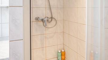 A walk-in shower with a glass door, a handheld showerhead, and a handheld shower attachment.
