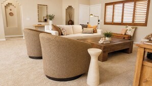 A living room with a beige sofa, two armchairs, a coffee table, and a decorative vase.