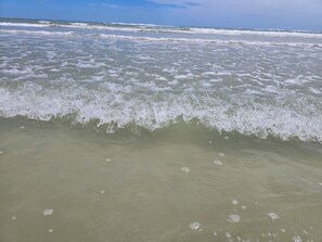 En strand med bølger der nærmer sig kysten.