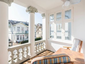 A balcony with a view of buildings, a table with a cushion, and a chair. - Holiday Apartment With 1 Bedroom (Heringsdorf)
