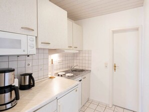 A compact kitchen with white cabinets, a microwave, a coffee maker, a sink, and a dishwasher. - Holiday Apartment With 1 Bedroom (Heringsdorf)