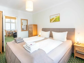 A hotel room with two beds, a dining area, a mirror, and a painting on the wall. - Holiday Apartment With 1 Bedroom (Heringsdorf)
