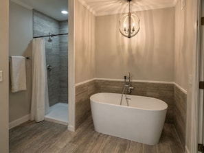 Une salle de bain moderne avec une baignoire sur pieds, un espace douche et un lustre.