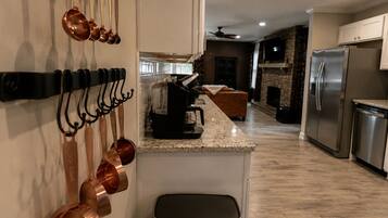 Una cocina moderna con electrodomésticos de acero inoxidable, encimera de granito y utensilios de cocina de cobre colgados en la pared.