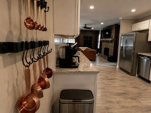 A modern kitchen with stainless steel appliances, a granite countertop, and copper cookware hanging on the wall.