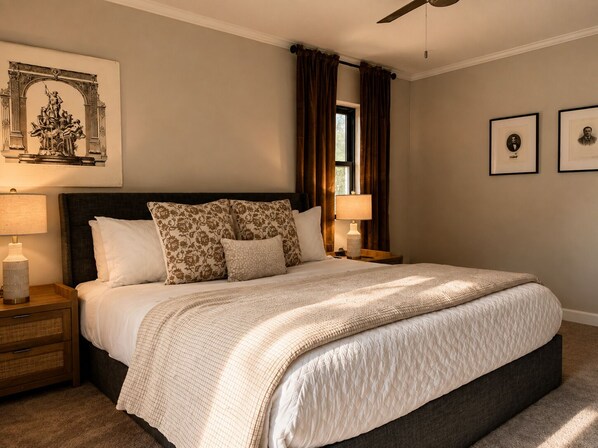 A bedroom with a large bed, two bedside tables, a ceiling fan, and a window with curtains.