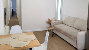 En moderne stue med sofa, spisebord med stole og et lille sofabord med fjernbetjening.