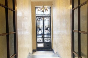 A hallway with a black wrought iron door, a chandelier, and a tiled floor. - 10- Incredible Apt. Privileged Location Recoleta (Buenos Aires)