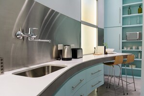 A modern kitchen with a stainless steel sink, a coffee maker, a toaster, and a bar stool. - 10- Incredible Apt. Privileged Location Recoleta (Buenos Aires)