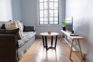A living room with a sofa, a round table, a TV on a stand, and a window with a view. - 10- Incredible Apt. Privileged Location Recoleta (Buenos Aires)
