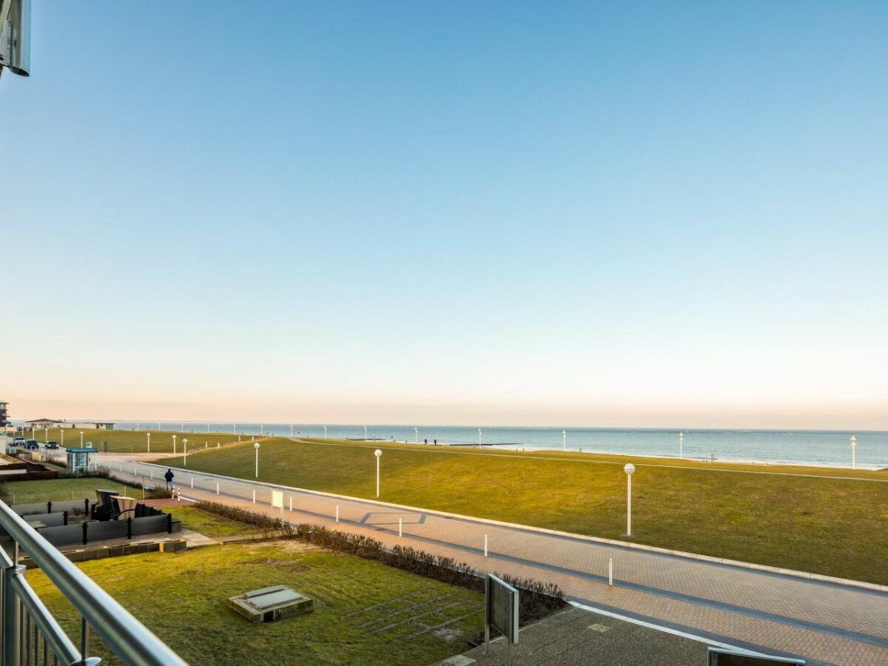 Un paseo marítimo con vistas despejadas al mar, una zona ajardinada y un sendero.