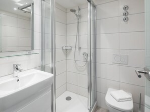 A modern bathroom with a glass-enclosed shower, a white sink, and a toilet. - Holiday Apartment in Norderney With Sauna (Norderney)