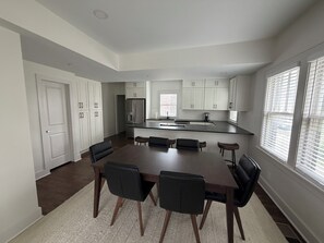 A modern kitchen with white cabinetry, a central island, and a dining area with a dark wooden table and black chairs. - 3-bedroom duplex in Dundee Omaha (Omaha)