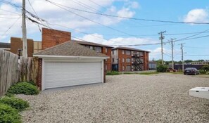 A residential area with a single garage, a brick building, and a gravel driveway. - 3-bedroom duplex in Dundee Omaha (Omaha)