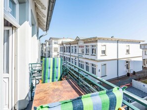 A balcony with a metal railing, a green and blue striped cushion, and a wooden table. - Holiday Apartment With 1 Bedroom (Heringsdorf)