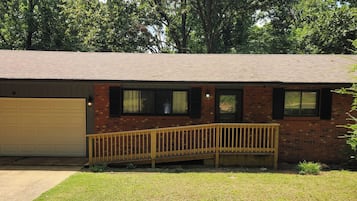 Un immeuble résidentiel doté d’un garage, d’une terrasse en bois et d’une cour gazonnée.