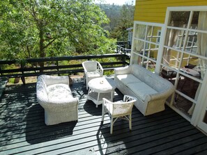 Eine Terrasse mit Korbohrmöbeln, darunter zwei Stühle und eine Couch, sowie ein Tisch.