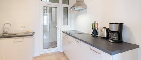 A modern kitchen with a built-in oven, a coffee maker, and a kettle.