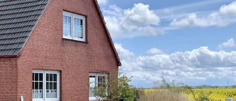 Una casa de ladrillo rojo con techo inclinado y cerca de madera.
