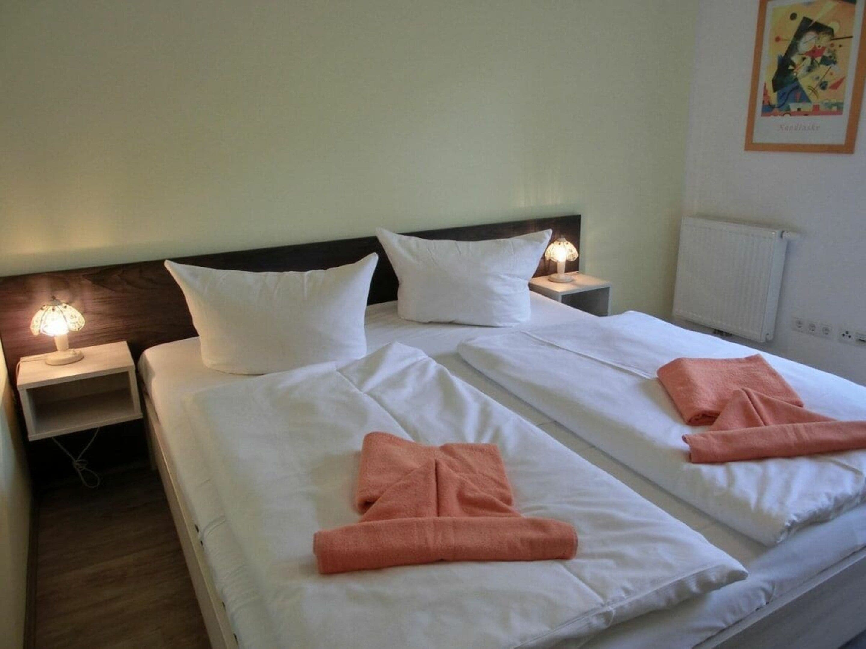 Ein Hotelzimmer mit zwei Betten, weißen Laken und passenden Kissen.