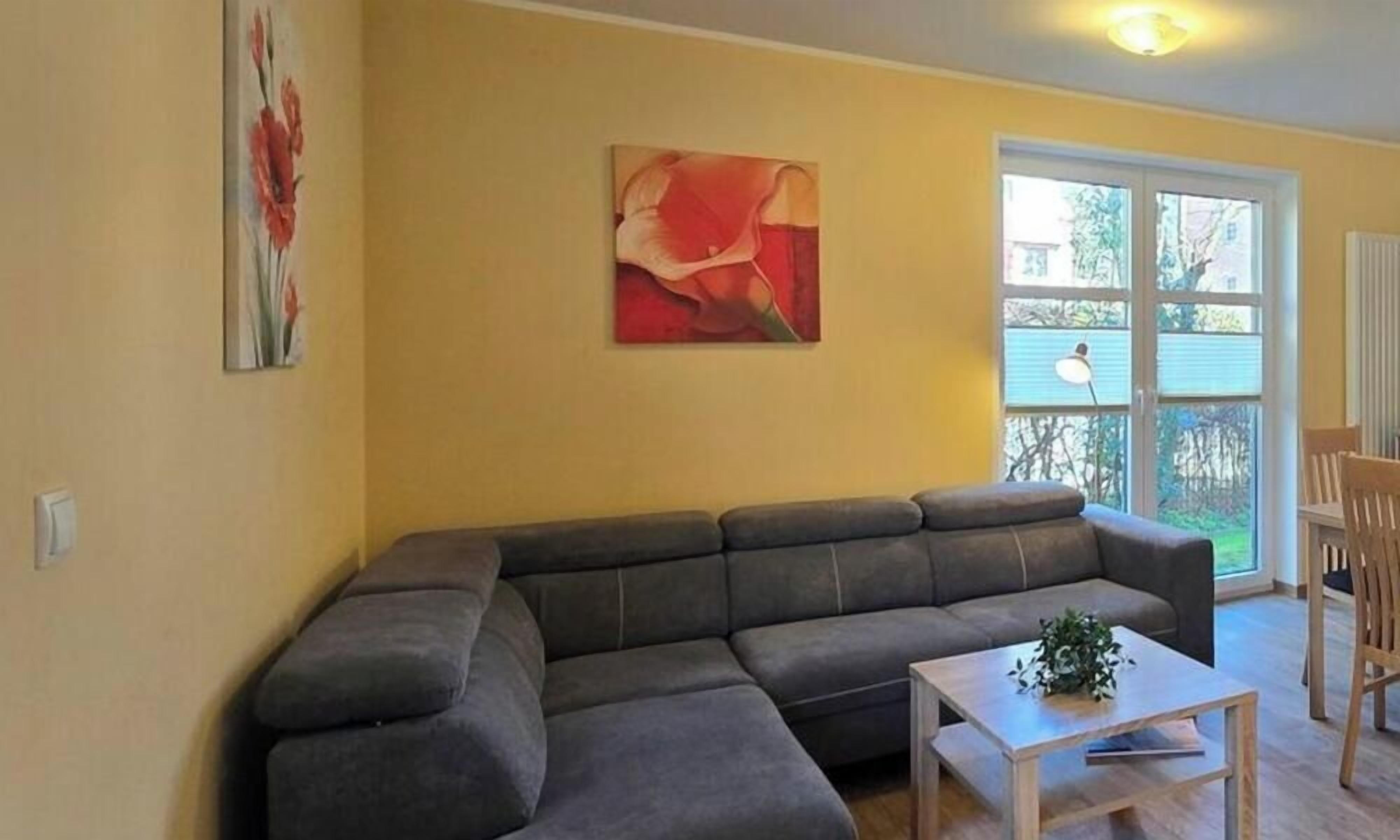 Una sala de estar con un sofá modular, una mesa de centro y dos cuadros en la pared.