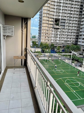 Un balcone con vista su un campo da basket e grattacieli.