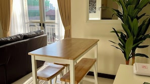 Ein modernes Wohnzimmer mit einem Holzesstisch, einer Couch und einem großen Fenster mit Vorhängen.