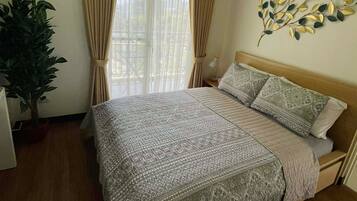 A bedroom with a bed, curtains, a wall-mounted plant, and a window with blinds.
