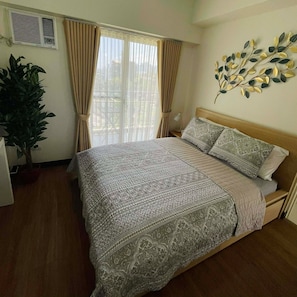A bedroom with a bed, curtains, a wall-mounted plant, and a window with blinds. - Lumiere Residences, Bright Large 2BR Condo w Balcony in Pasig (Pasig)