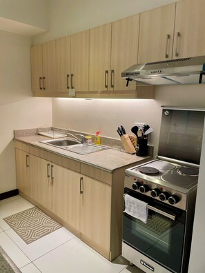 A modern kitchen with wooden cabinets, a stainless steel stove, and a sink. - Lumiere Residences, Bright Large 2BR Condo w Balcony in Pasig (Pasig)