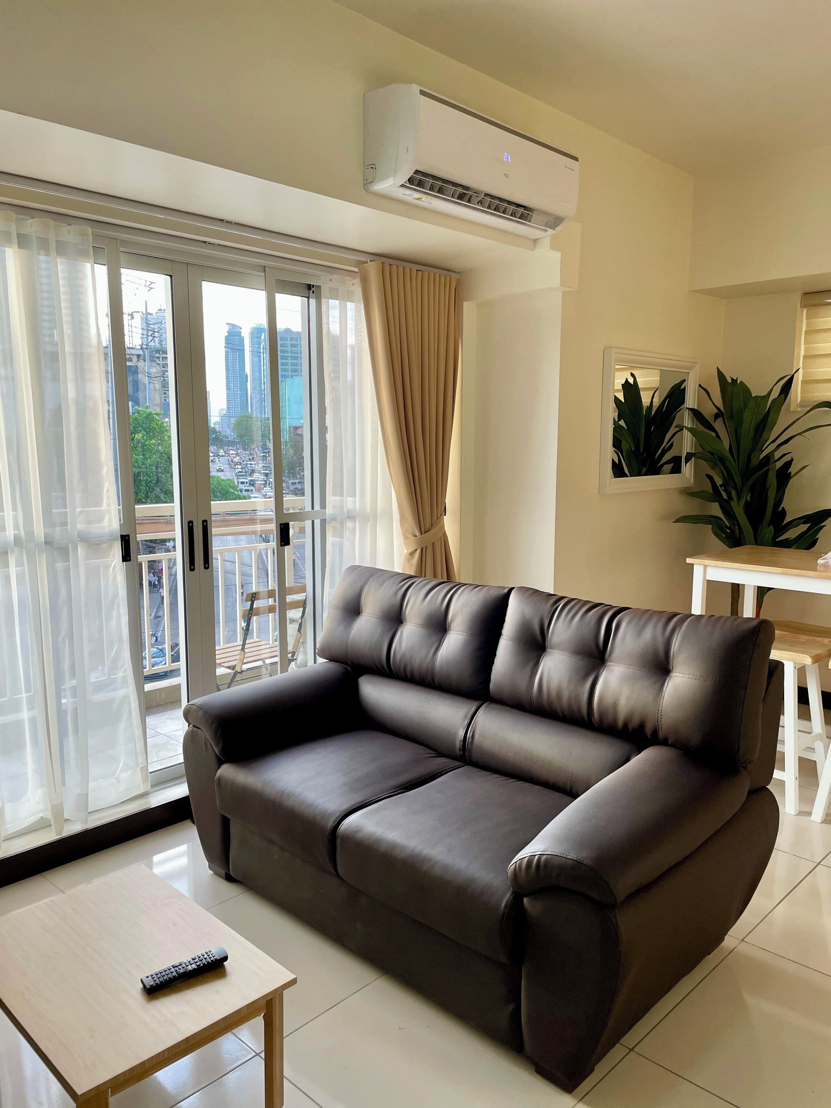 A modern living room with a leather sofa, a small wooden table, and a remote control on it.
