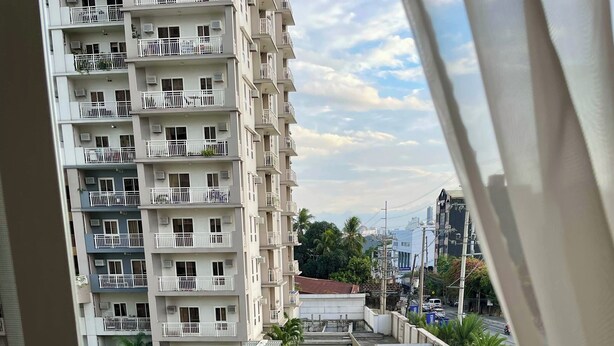 Ein Balkon mit Blick auf ein mehrstöckiges Gebäude, eine Straße und etwas Grün.