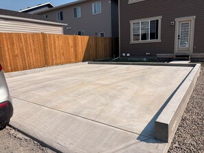 A residential driveway with a concrete surface, a wooden fence, and a vehicle parked on the left. - Fabulous 4-bedroom house with 3 full bath l ACs in all rooms l Sleeps 8 plus  (Calgary)